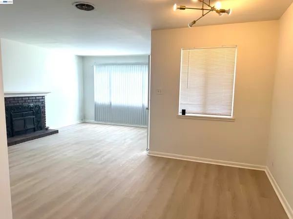 an empty room with wooden floor fireplace and windows