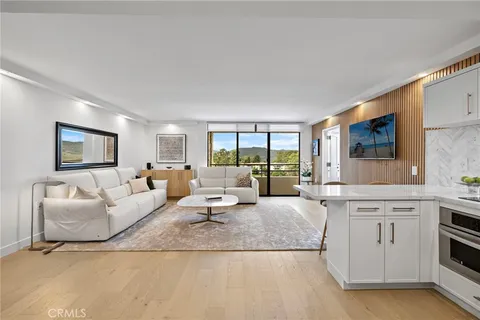 a living room with furniture large window and wooden floor