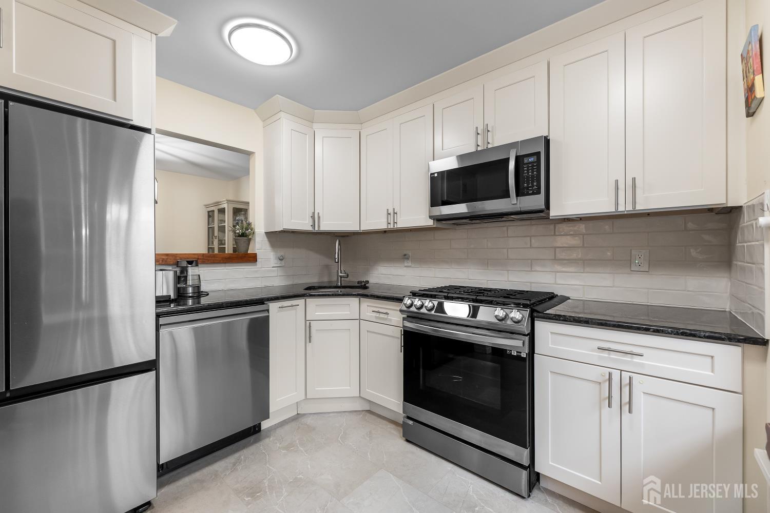 7 Edith Drive Somerset, NJ 08873 - Photo 12 of 49 a kitchen with stainless steel appliances granite countertop white cabinets a sink a stove a refrigerator and a microwave