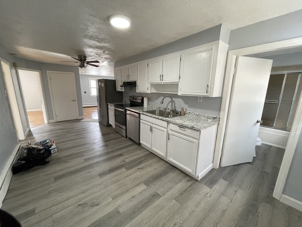 72 Longfellow Road Worcester, MA 01602 - Photo 22 of 36 a kitchen with stainless steel appliances granite countertop a stove a refrigerator a sink and white cabinets with wooden floor
