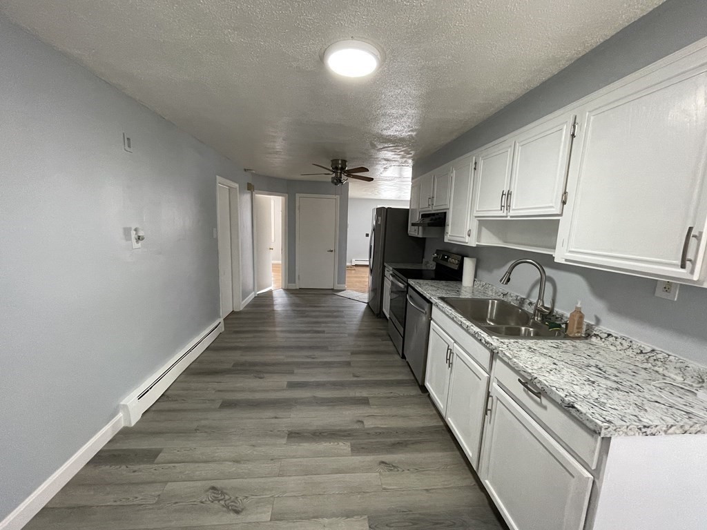 72 Longfellow Road Worcester, MA 01602 - Photo 6 of 36 a large kitchen with granite countertop a stove top oven a sink dishwasher and white cabinets with wooden floor