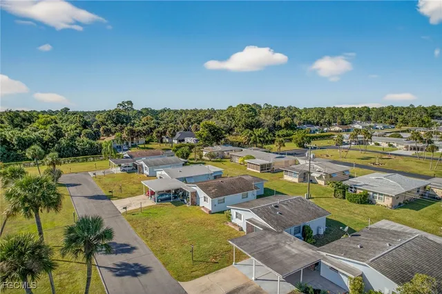 an aerial view of a swimming pool with seating area and trees in the background
