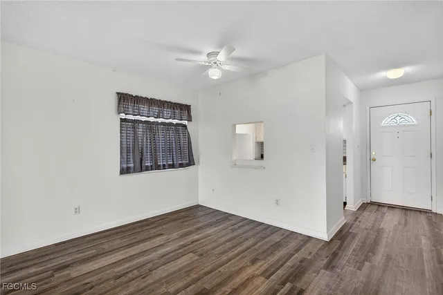 a view of an empty room with wooden floor and a ceiling fan