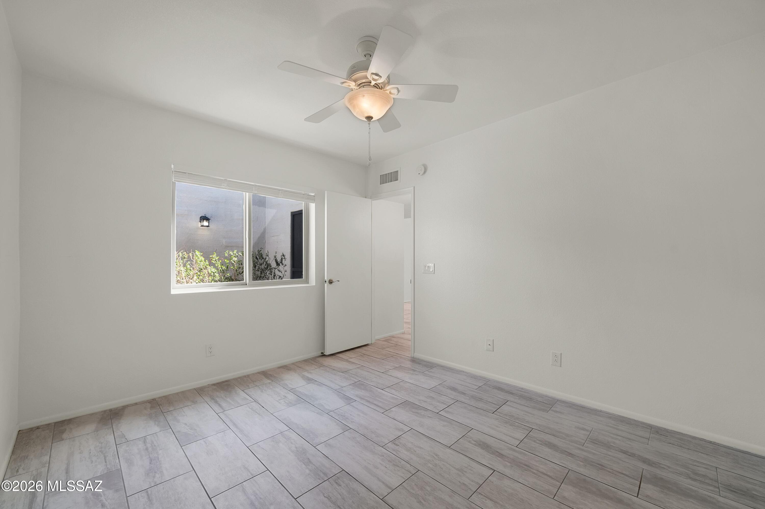 7408 East Wandering Road Tucson, AZ 85750 - Photo 21 of 25 a view of an empty room with chandelier fan and window