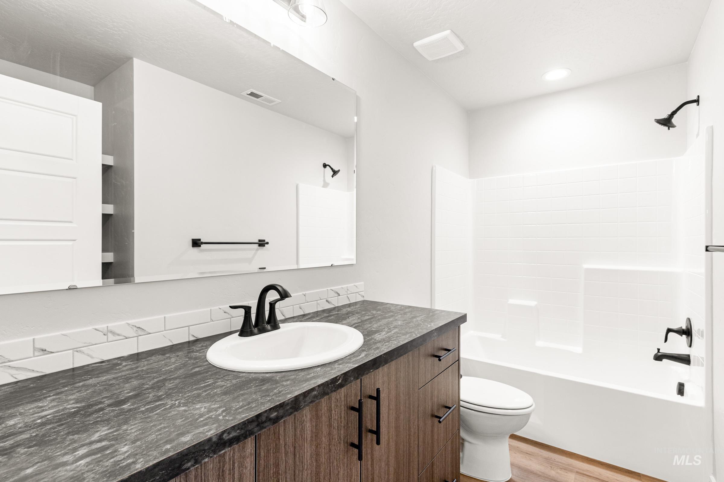 12830 Ropers Street Nampa, ID 83651 - Photo 16 of 18 Bathroom featuring a wood-finish vanity with dark hardware, a single basin sink, and a dark stone-look countertop