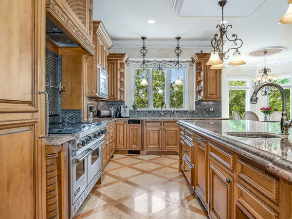a kitchen with stainless steel appliances granite countertop a sink a stove and a refrigerator