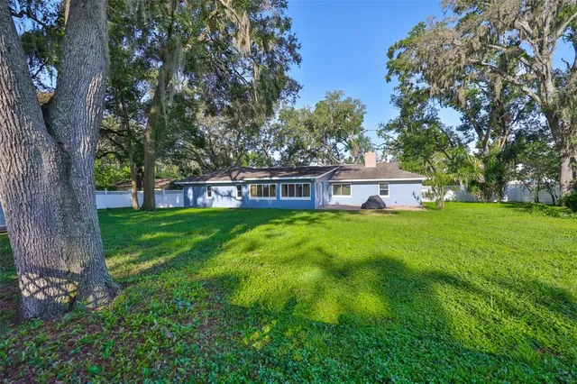 a view of a house with a big yard and large trees