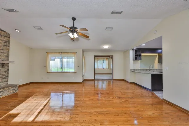 a view of an empty room with window and wooden floor