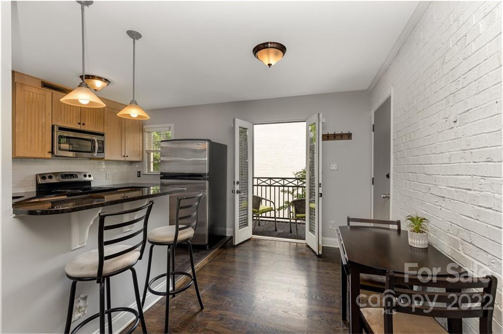 4915 Park Road, Unit C Charlotte, NC 28209 - Photo 3 of 22 a kitchen with stainless steel appliances granite countertop a stove top oven a sink dishwasher a dining table and chairs with wooden floor