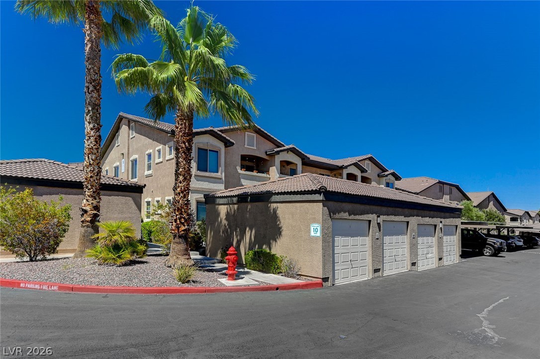 8985 South Durango Drive, Unit 2187 Las Vegas, NV 89113 - Photo 57 of 73 Showcasing a multi-level complex, this property boasts garages and covered parking under towering palms.