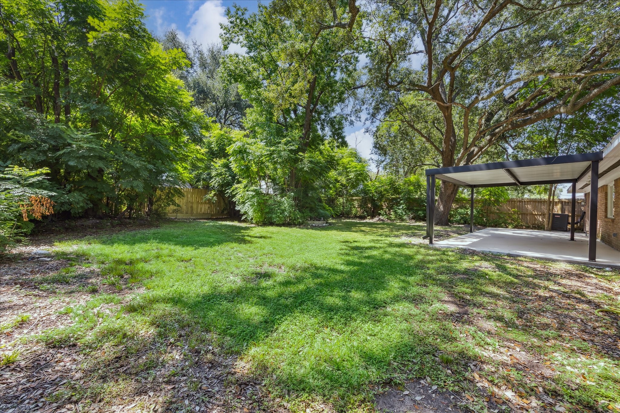 5419 Beechnut Street Houston, TX 77096 - Photo 25 of 28 Expansive backyard space with greenery and tree canopy, offering shade, privacy, and room to enjoy the outdoors.