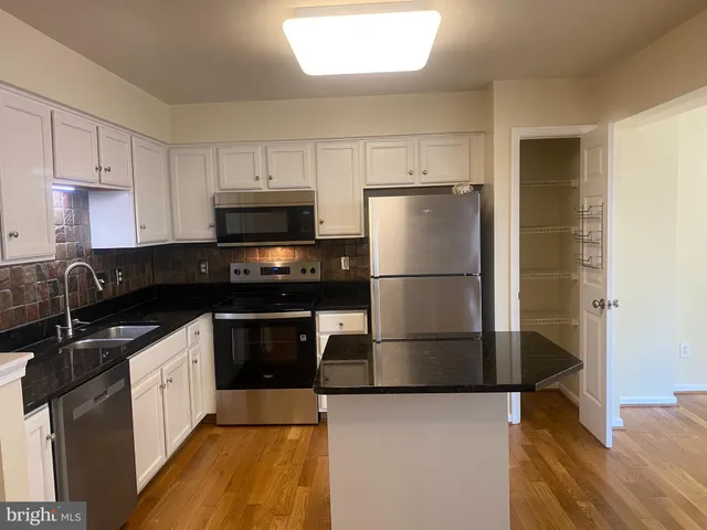 a kitchen with kitchen island a refrigerator a stove a sink and white cabinets