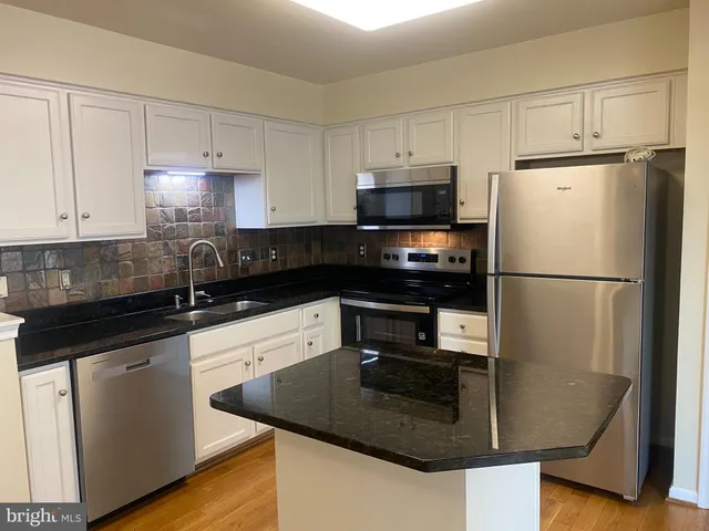 a kitchen with granite countertop a refrigerator stove and microwave