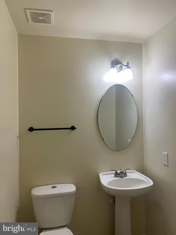 a view of an empty room with wooden floor and fan