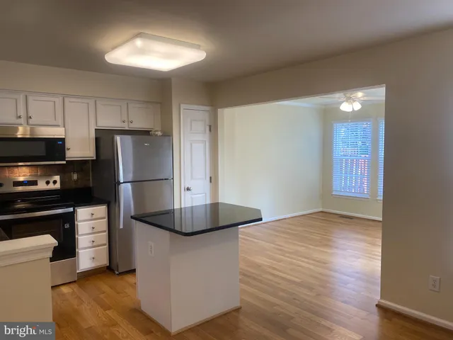 a kitchen with stainless steel appliances granite countertop a stove a sink and white cabinets