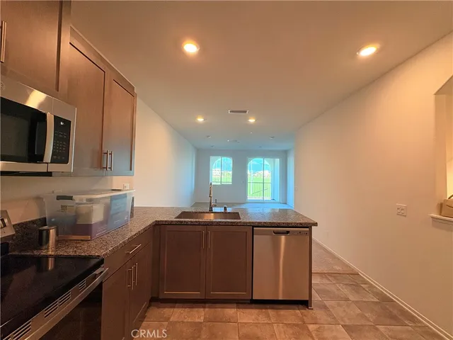 a kitchen with stainless steel appliances granite countertop a sink a stove top oven a counter space and cabinets