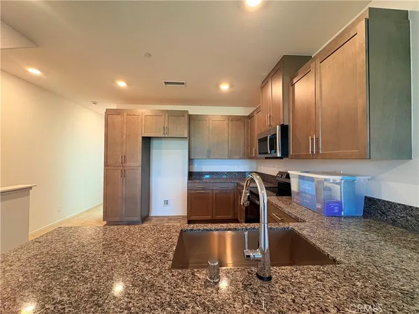 a kitchen with stainless steel appliances granite countertop a sink and a refrigerator