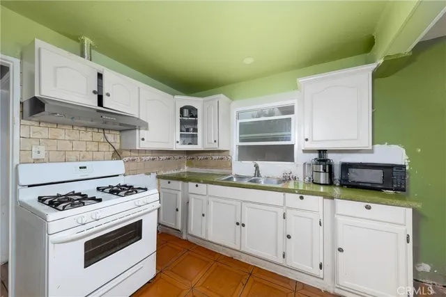 a kitchen with stainless steel appliances white cabinets and a stove top oven