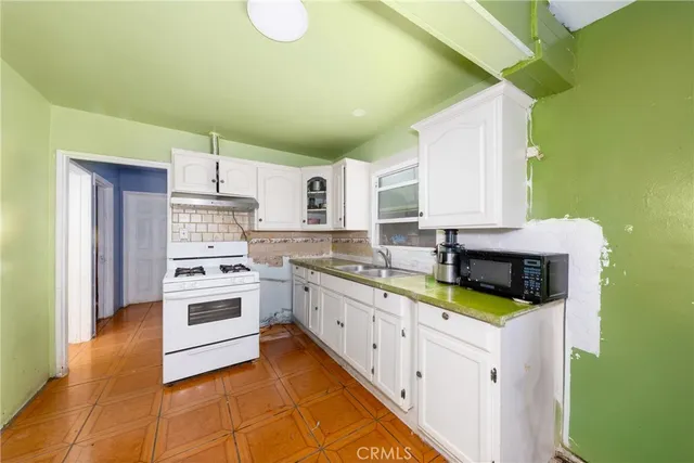 a kitchen with stainless steel appliances a stove a sink and white cabinets
