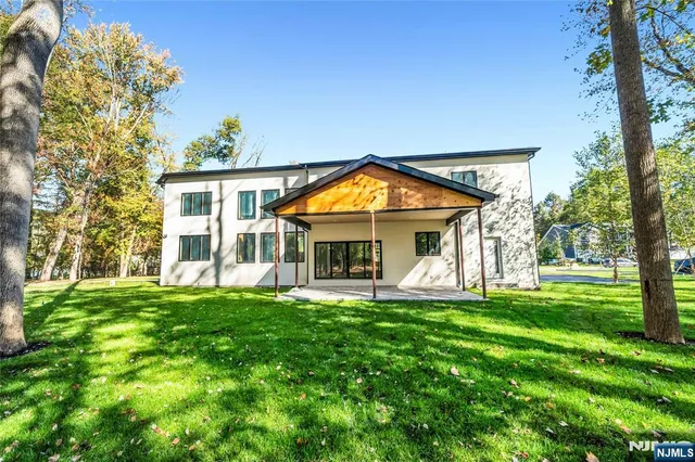 a view of a white house with a large pool lawn chairs and a yard with wooden fence