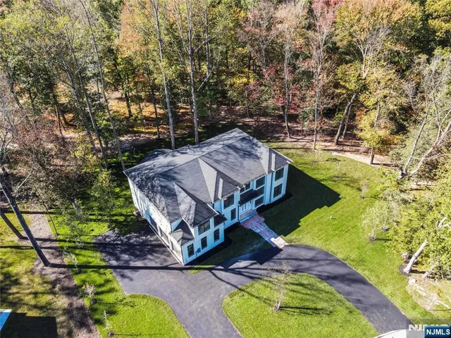 an aerial view of residential house with outdoor space and trees all around