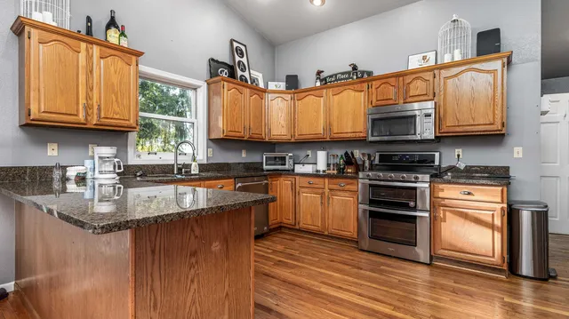 a kitchen with stainless steel appliances granite countertop a sink a stove a microwave and cabinets