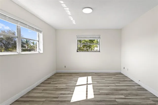 a view of empty room with window and wooden floor