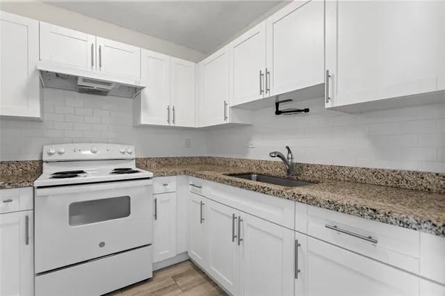 a kitchen with granite countertop white cabinets and white appliances