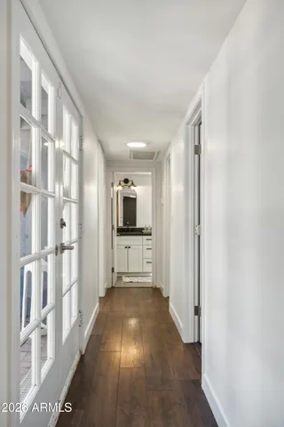 a view of a hallway with a livingroom with wooden floor and a kitchen space