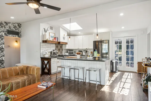 a kitchen with stainless steel appliances granite countertop a stove top oven a refrigerator a dining table and chairs with wooden floor