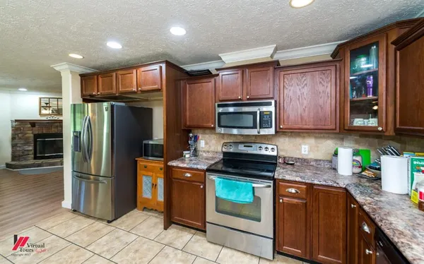 a kitchen with granite countertop a refrigerator and a stove top oven