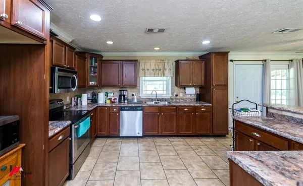 a large kitchen with stainless steel appliances granite countertop a large counter top a stove a sink and a refrigerator