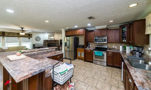 a kitchen with stainless steel appliances granite countertop a sink refrigerator and cabinets