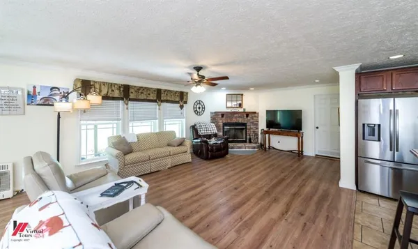 a living room with furniture a flat screen tv and a refrigerator
