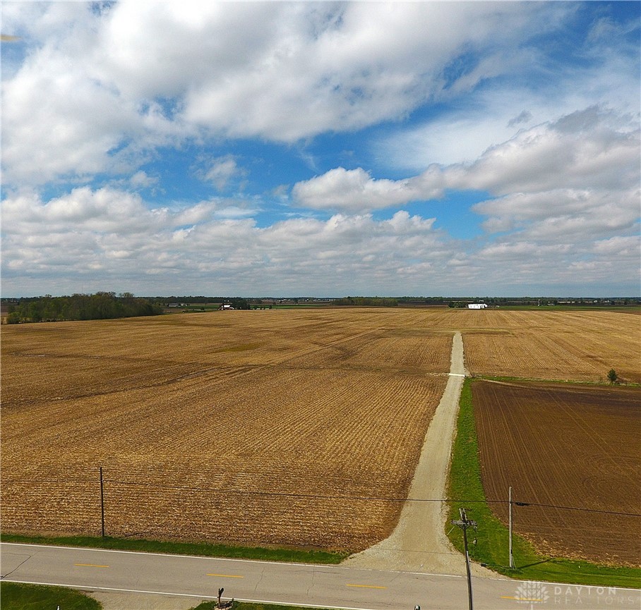 6468 Requarth Road Greenville, OH 45331 - Photo 1 of 4 Expansive fields stretch towards the horizon under a vast, cloud-filled sky.