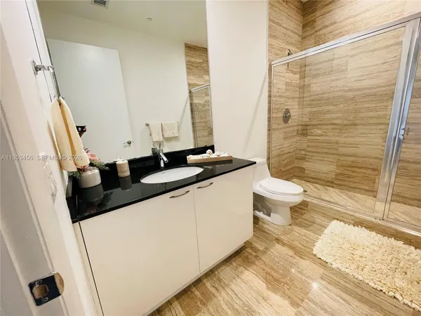 a bathroom with a sink a toilet a mirror and shower