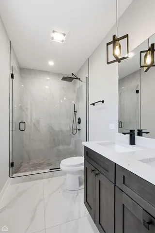 a bathroom with a granite countertop toilet a sink and shower