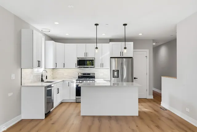 a kitchen with stainless steel appliances granite countertop a sink a stove a refrigerator cabinets and dining table