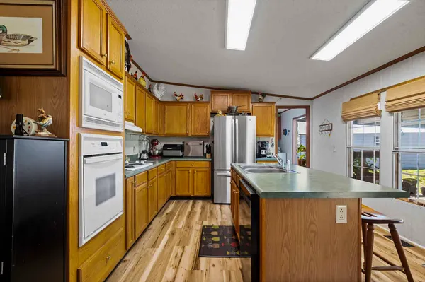 a kitchen with stainless steel appliances granite countertop a refrigerator a sink dishwasher a stove and a dining table with wooden floor