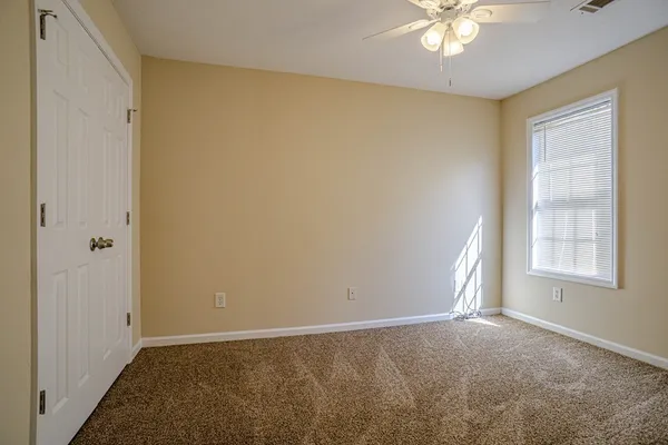 an empty room with windows and chandelier fan
