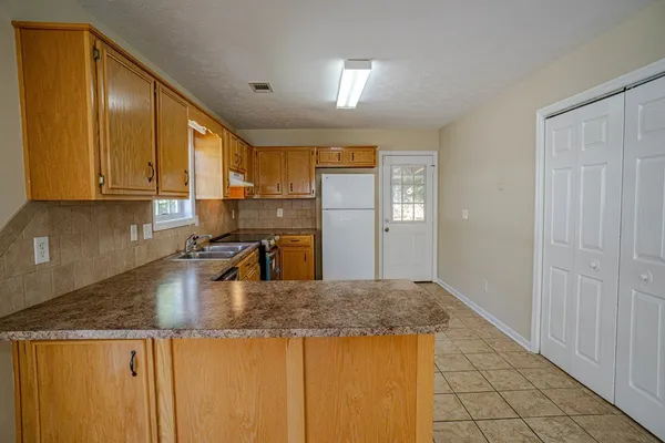 a kitchen with granite countertop a sink a stove and refrigerator