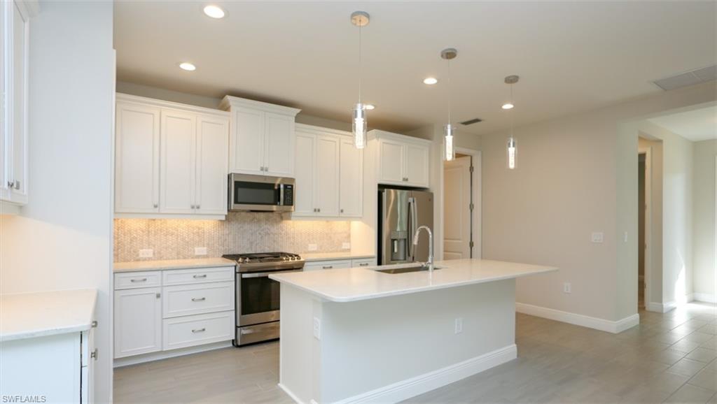 2428 Ariane Drive Naples, FL 34112 - Photo 2 of 23 a kitchen with white cabinets and stainless steel appliances