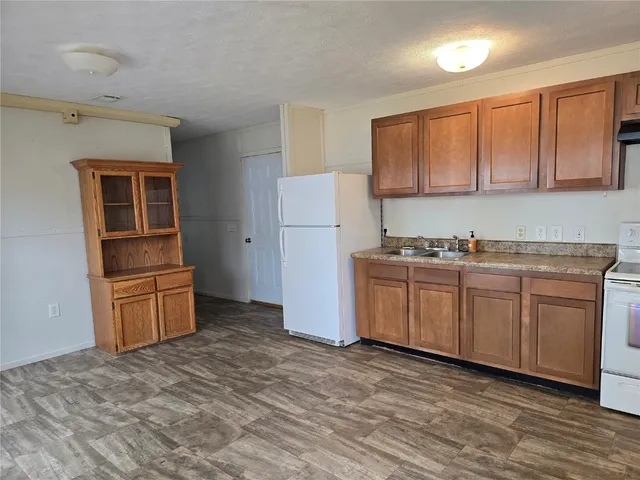 a kitchen with granite countertop a refrigerator stove top oven and sink