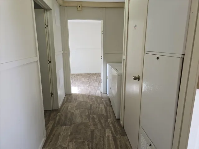 a view of a hallway with wooden floor and a bathroom