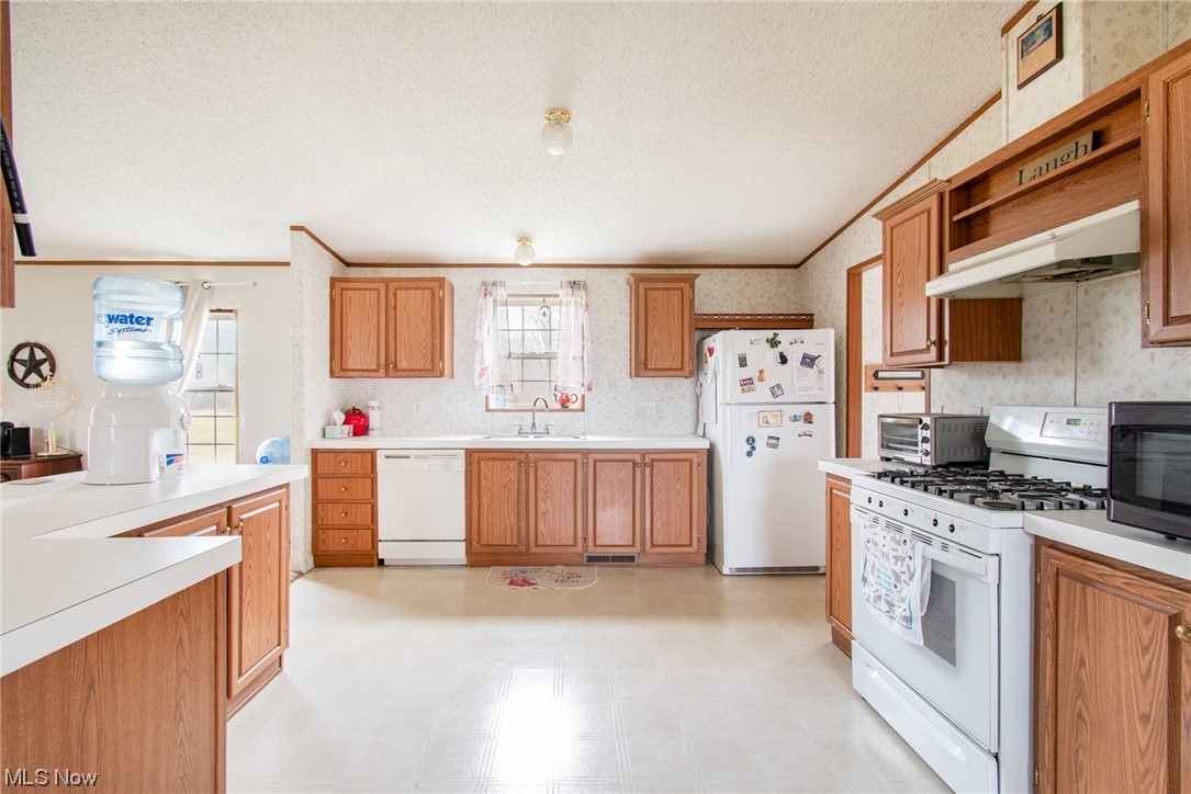 10135 Williams Road Diamond, OH 44412 - Photo 11 of 30 Kitchen with ornamental molding, white appliances, light tile floors, and a textured ceiling