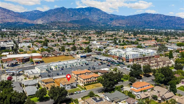 an aerial view of a city with lots of residential buildings ocean and mountain view in back