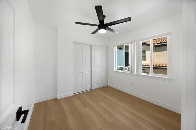 a view of empty room with wooden floor and fan