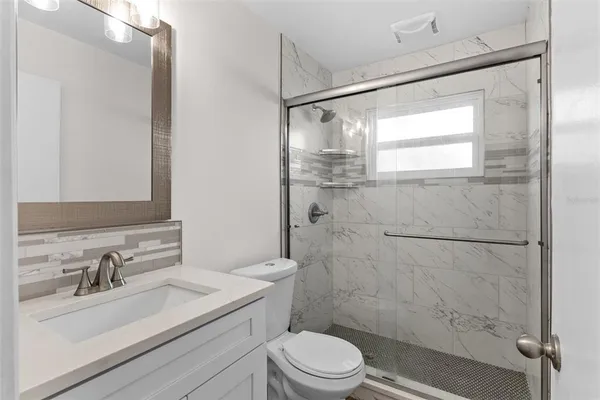 a bathroom with a sink toilet a mirror and shower