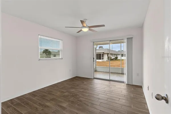 a view of an empty room with window and wooden floor