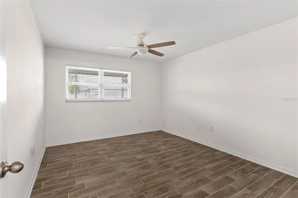an empty room with a window and ceiling fan